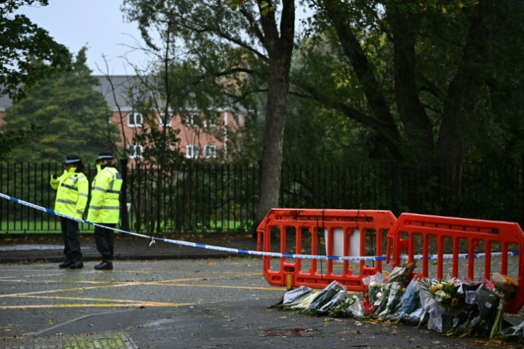 Des policiers près de fleurs déposées à l'extérieur de la synagogue d'Heaton Park, à Crumpsall, au nord de Manchester, le 4 octobre 2025 en Angleterre ( AFP / Paul ELLIS )
