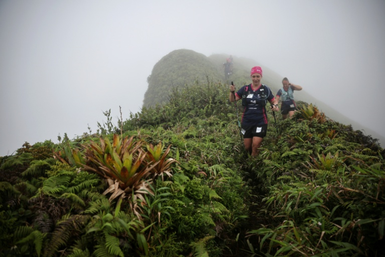 Sonia Latapie (d), souffrant d'insuffisance rénale et atteinte d'un cancer du sein, membre de l'équipe "Les Reines du cœur", participe avec sa coéquipière Alexia Elineau (c) à la course de trail sur la Montagne Pelée, près de Saint-Pierre, lors du "Raid des Alizé", le 28 novembre 2025 en Martinique ( AFP / Anne-Christine POUJOULAT )