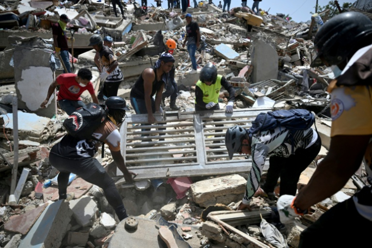 Des bénévoles soulèvent une grille métallique tout en fouillant les décombres de bâtiments effondrés à Catia La Mar, dans l'État de La Guaira, le 26 juin 2026 après deux séismes meurtriers au Venezuela ( AFP / Federico PARRA )