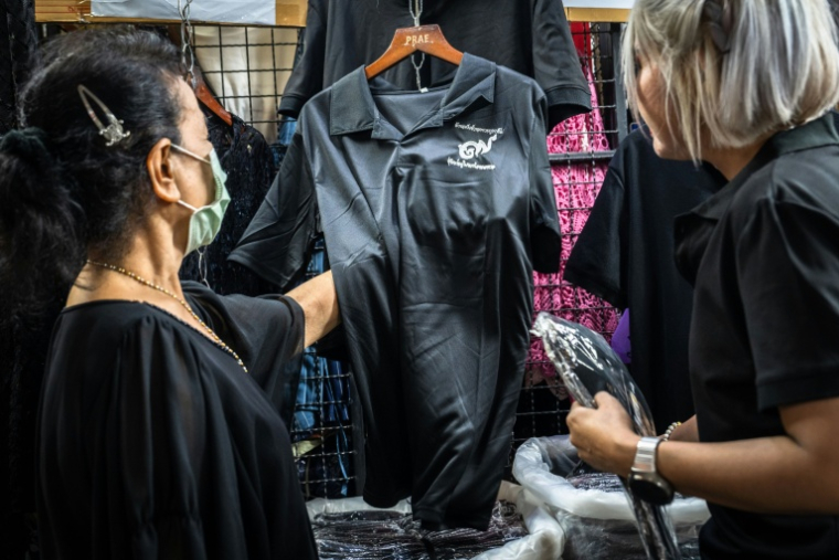 Des clients achètent des vêtements noirs à Bangkok le 30 ocobre 2025 pour porter le deuil après le décès de la reine mère Sirikit,  décédée à 93 ans ( AFP / Chanakarn Laosarakham )