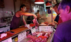Un vendeur de porc s'occupe d'un client sur un marché matinal à Pékin