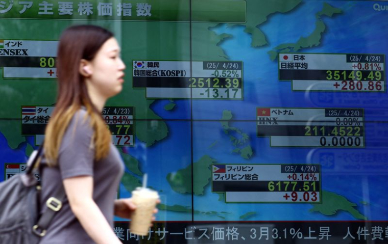 Une femme passe devant un écran électronique affichant les indices boursiers des pays asiatiques à l'extérieur d'une maison de courtage à Tokyo