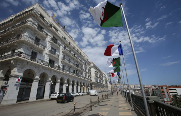 Des véhicules passent devant les drapeaux algériens et français, avant l'arrivée du président français Emmanuel Macron à Alger