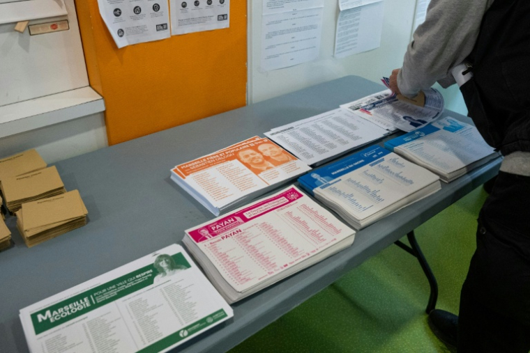 Un citoyen prend ses bulletins de vote avant de se rendre à l'isoloir dans un bureau de vote à Marseille le 15 mars 2026 ( AFP / Elodie CLEMENT )