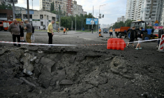 Des habitants de Kiev passent près d'un cratère causé par une frappe de missile russe sur la capitale de l'Ukraine, le 11 juillet 2026 ( AFP / Genya Savilov )