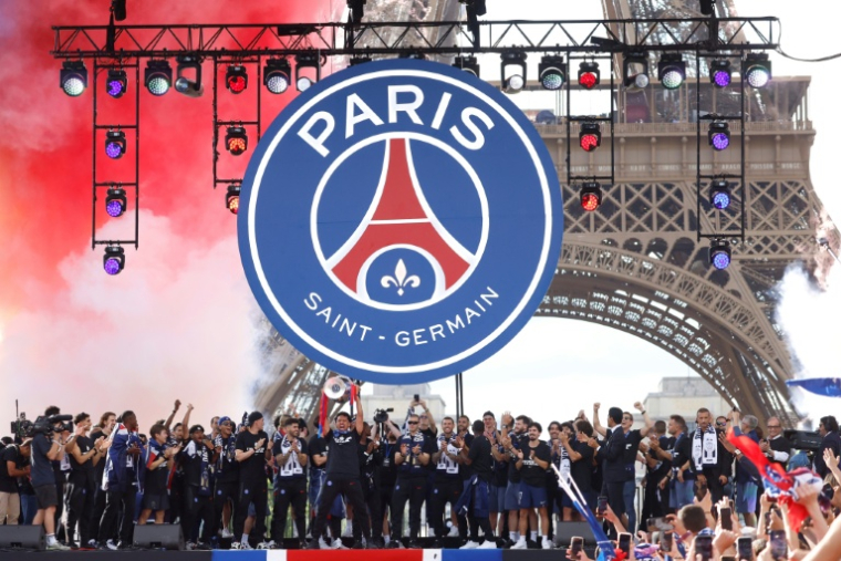 Les joueurs du Paris Saint-Germain dont leur capitaine Marquinhos, qui soulève la coupe en centre, accueilli en héros au Champ-de-Mars, le 31 mai 2026, au lendemain de leur triomphe en Ligue des champions ( AFP / Kenzo TRIBOUILLARD )