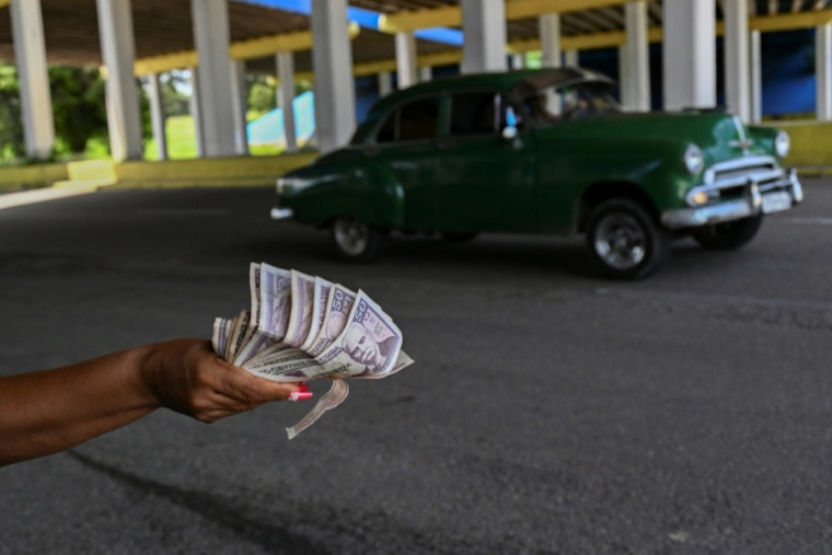 Une femme tient des billets de banque sur l'autoroute nationale, en périphérie de La Havane, le 16 juin 2026 ( AFP / YAMIL LAGE )