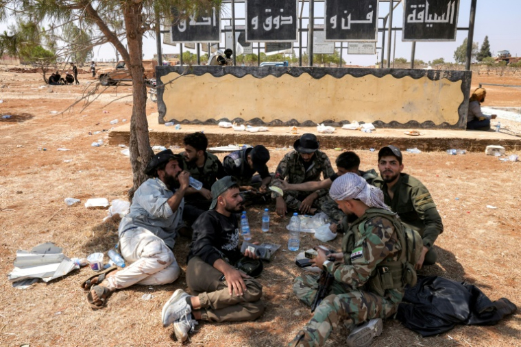 Des combattants tribaux se reposent près d'un barrage mis en place par les forces gouvernementales après leur déploiement à Busra al-Harir, dans la province de Deraa, dans le sud de la Syrie, le 21 juillet 2025 ( AFP / Bakr ALkasem )