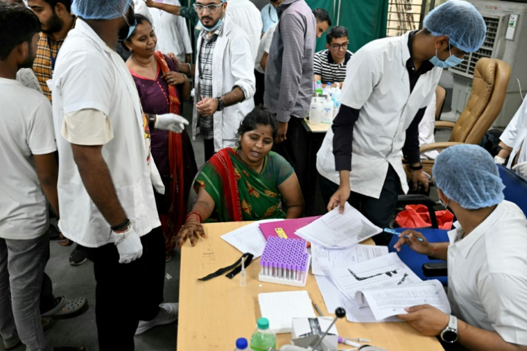 Des membres des médicaux collectent des échantillons d'ADN auprès de proches pour identifier les victimes du crash du vol 171 d'Air India, dans un centre d'urgence à Ahmedabad, le 13 juin 2025 ( AFP / Punit PARANJPE )