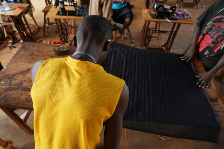 Un élève, ancien enfant soldat, découpe un morceau de tissu lors d'un cours de couture au Centre de formation professionnelle pratique et d’alphabétisation de Bria, en Centrafrique, le 1er avril 2026 ( AFP / Mariam KONE )