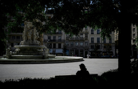 Une personne est assise à l'ombre sur la place des Jacobins, le 25 juin 2025 à Lyon ( AFP / JEFF PACHOUD )