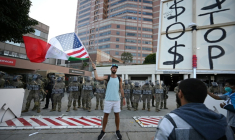 Un homme brandit un drapeau aux couleurs des Etats-Unis et du Mexique devant des membres de la Garde nationale, à Los Angeles (Californie), le 12 juin 2025 ( AFP / Robyn Beck )