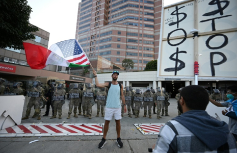 Un homme brandit un drapeau aux couleurs des Etats-Unis et du Mexique devant des membres de la Garde nationale, à Los Angeles (Californie), le 12 juin 2025 ( AFP / Robyn Beck )