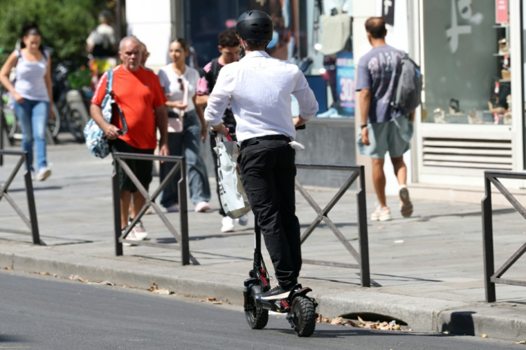 Un homme roule en trottinette électrique dans une rue de Paris, le 11 août 2026 ( AFP / Kenzo TRIBOUILLARD )