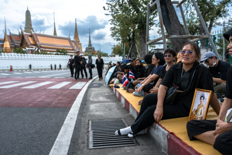 Des Thaïlandais en deuil attendent le passage du cortège funéraire après le décès de la reine mère Sirikit, le 26 octobre 2025 à Bangkok ( AFP / Chanakarn Laosarakham )