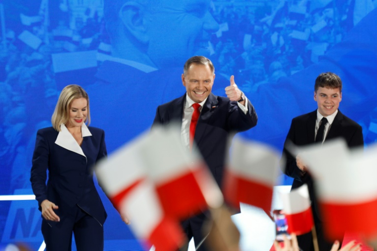 Karol Nawrocki, accompagné de son épouse Marta, salue ses partisans après l'annonce des sondages de sortie des urnes, lors du deuxième tour de la présidentielle, le 1er juin 2025 à Varsovie, en Pologne ( AFP / Wojtek RADWANSKI )