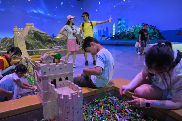 Des enfants jouent à côté d'une réplique de la Grande Muraille de Chine, au parc Legoland de Shanghai ( AFP / Hector RETAMAL )