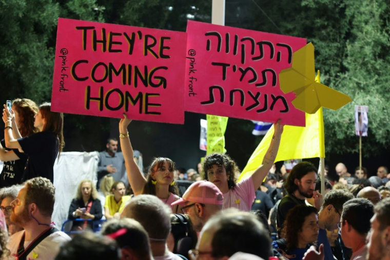 Des femmes brandissent des pancartes lors d’un rassemblement sur la place des Otages à Tel-Aviv, en Israël, avant la libération prévue de dizaines d'otages retenus dans la bande de Gaza, le 11 octobre 2025 ( AFP / Jack GUEZ )
