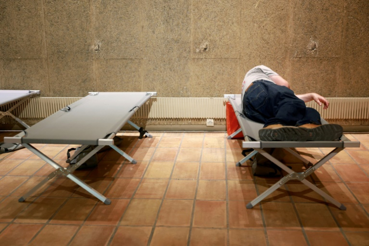 Une personne se repose sur un lit de camp au centre d'accueil Jean Moulin à Bordeaux, dans le sud-ouest de la France, le 11 août 2025.  ( AFP / ROMAIN PERROCHEAU )