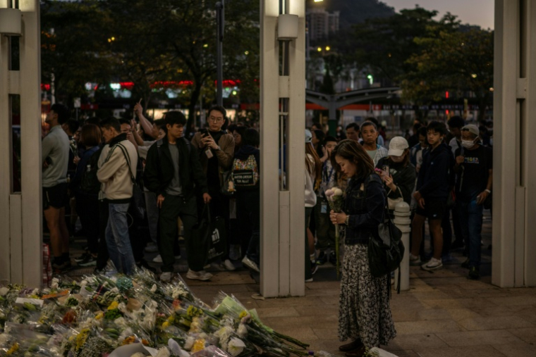 Des habitants de Hong Kong déposent des fleurs devant un complexe résidentiel ravagé par un incendie, le 29 novembre 2025 ( AFP / Philip FONG )