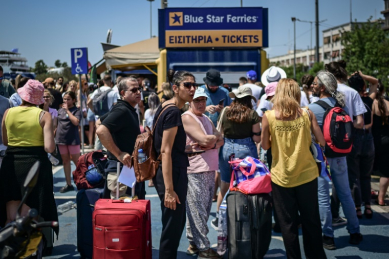 Des passagers attendent un ferry dans le port du Pirée, près d'Athènes, le 8 août 2025 ( AFP / Aris MESSINIS )