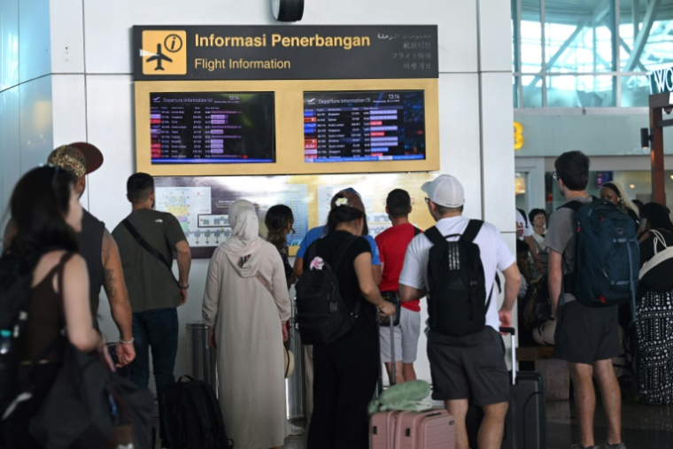 Des voyageurs regardent les tableaux d'information affichant les vols annulés après l'éruption du mont Lewotobi Laki-Laki, à l'aéroport international Ngurah Rai de Tuban, près de Denpasar, sur l'île touristique de Bali, le 18 juin 2025 en Indonésie ( AFP / SONNY TUMBELAKA )