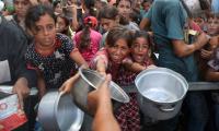 De jeunes palestiniens attendent de recevoir des repas cuisinés dans le camp de réfugiés de Nousseirat, dans le centre de la bande de Gaza, le 18 août 2025 ( AFP / Eyad BABA )