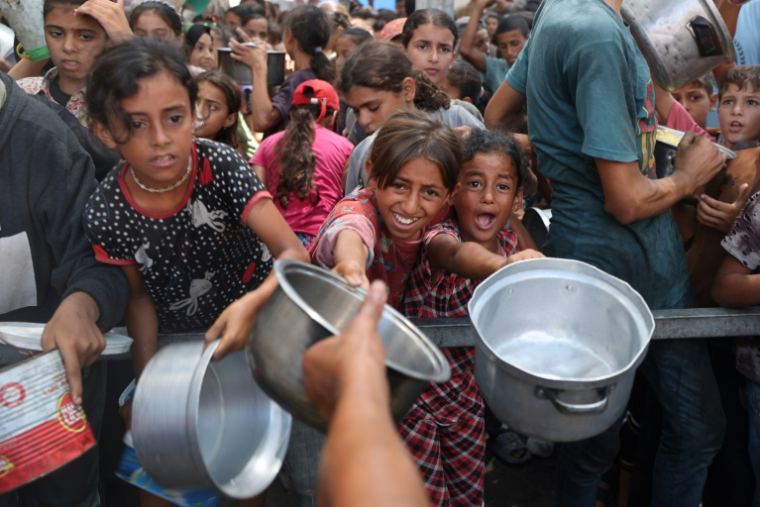 De jeunes palestiniens attendent de recevoir des repas cuisinés dans le camp de réfugiés de Nousseirat, dans le centre de la bande de Gaza, le 18 août 2025 ( AFP / Eyad BABA )