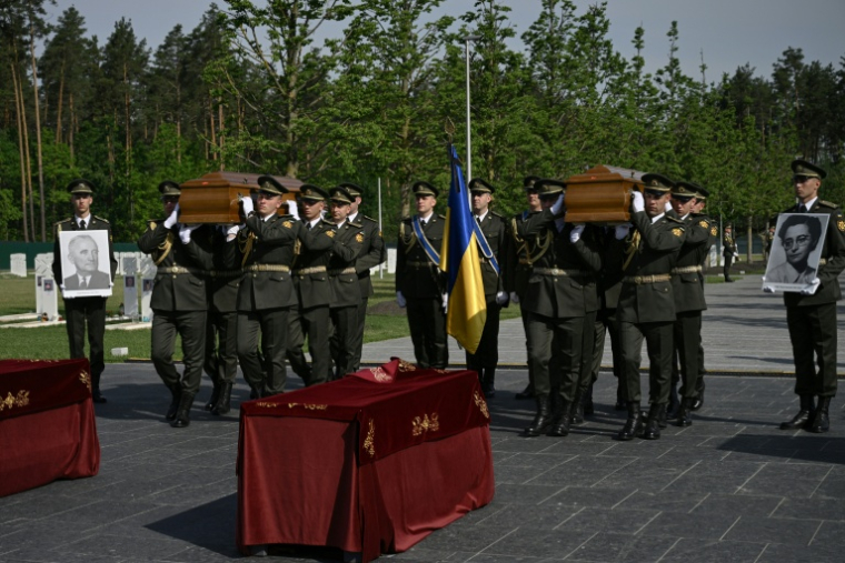 Des soldats ukrainiens portent les cercueils du leader nationaliste controversé Andriï Melnyk et de son épouse Sofia, lors d'une cérémonie de réinhumation au cimetière national militaire commémoratif près de Kiev, le 25 mai 2026 ( AFP / Genya SAVILOV )