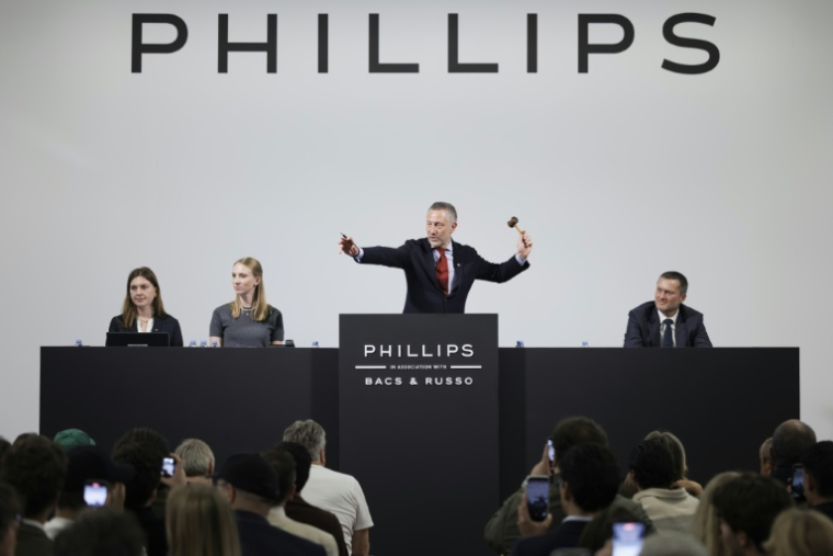 Le commissaire-priseur Aurel Bacs (au centre) lève le marteau lors de la vente aux enchère d'une rare montre Patek Philippe, le 8 novembre 2025 à Genève (Suisse) ( AFP / Valentin Flauraud )