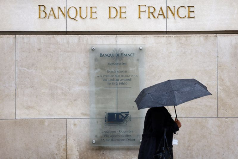 Une femme tenant un parapluie passe devant le bâtiment de la Banque de France à Paris