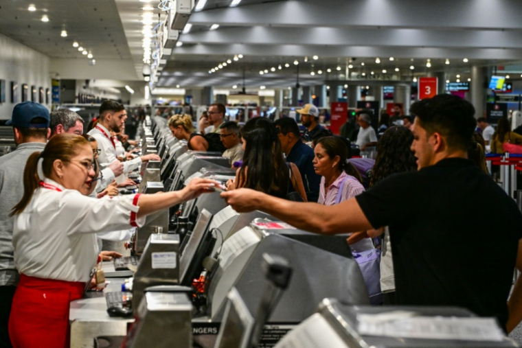 Des voyageurs présentent leurs documents aux personnels d'une compagnie aérienne à l'aéroport international de Miami, le 24 mai 2025 en Floride ( AFP / Giorgio VIera )
