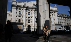 Une personne fait du vélo près de la Bourse de Milan (bourse italienne)