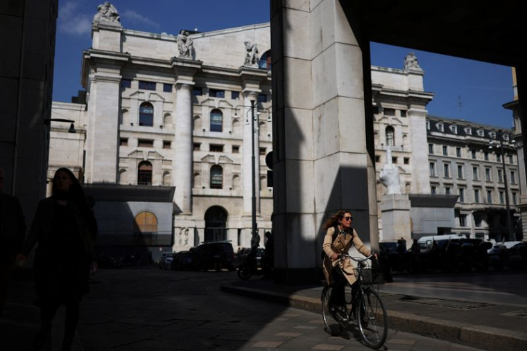 Une personne fait du vélo près de la Bourse de Milan (bourse italienne)