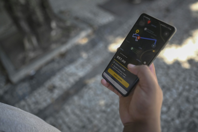 Joao Paulo Teixeira, 20 ans, livreur de repas, vérifie l'adresse de son prochain client sur l'application de livraison de repas dans le centre-ville de Rio de Janeiro, au Brésil, le 17 avril 2026.   ( AFP / Mauro PIMENTEL )