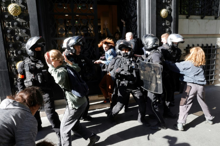 Des policiers repoussent des membres d'Extinction Rebellion (XR) lors d'une manifestation devant les bureaux de la banque BNP Paribas, avant l'assemblée générale ordinaire et extraordinaire des actionnaires de TotalEnergies, le 23 mai 2025 à Paris ( AFP / GEOFFROY VAN DER HASSELT )