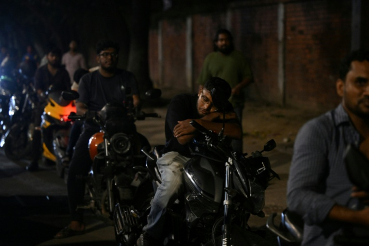 Un homme fait la sieste sur sa moto dans une file d'attente pour du carburant à Dacca, capitale du Bangladesh, le 21 avril 2026 ( AFP / MUNIR UZ ZAMAN )