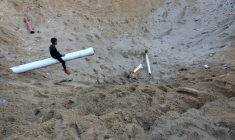 Un enfant palestinien est assis sur un bout d'une conduite d'eau dans un immense cratère provoqué par un raid israélien à Gaza-ville, le 28 juin 2025 ( AFP / Omar AL-QATTAA )