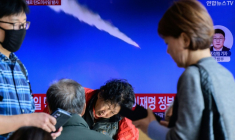 Des passants regardent une télévision diffusant un journal télévisé avec des images d'archives d'un essai de missile nord-coréen, dans une gare de Séoul, le 7 novembre 2025 ( AFP / ANTHONY WALLACE )