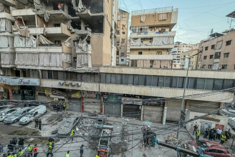 Des personnes ramassent des gravats sur le site d'une frappe israélienne dans la banlieue sud de Beyrouth le 23 novembre 2025. ( AFP / Ibrahim AMRO )