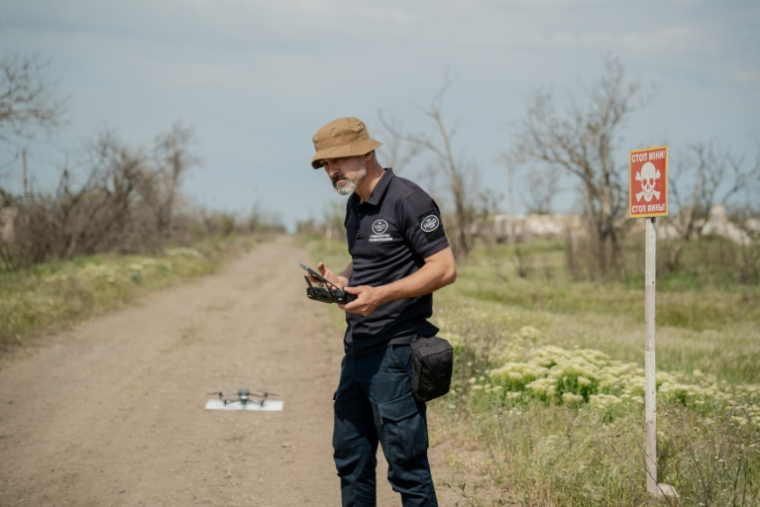 Un responsable de HALO Trust lance un drone pour chercher les mines dans le village de Bezymenne, dans la région de Mykolaiv, le 5 mai 2025 ( AFP / Ivan SAMOILOV )