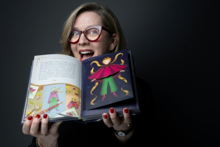 Miraphora Mina du studio MinaLima pose avec le nouvel album du "Petit Prince", le 2 avril 2026 à Paris  ( AFP / JOEL SAGET )