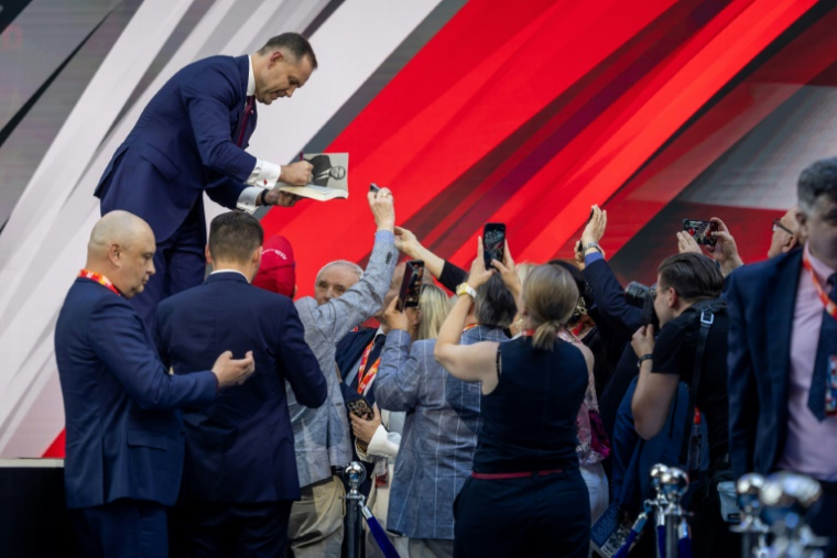 Le candidat à la présidentielle Karol Nawrocki signe son livre pour ses partisans lors d'un meeting de campagne à Jasionka, le 27 mai 2025 en Pologne ( AFP / Wojtek RADWANSKI )