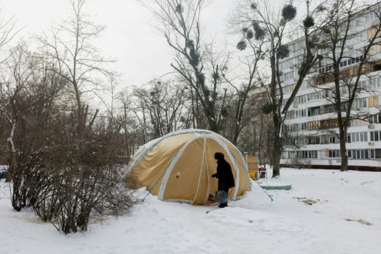 Une femme entre dans une tente proposant des services d'urgence, installée pour les personnes dont les logements sont privés d'électricité ou de chauffage, à Kiev, le 18 février 2026 ( AFP / Tetiana DZHAFAROVA )