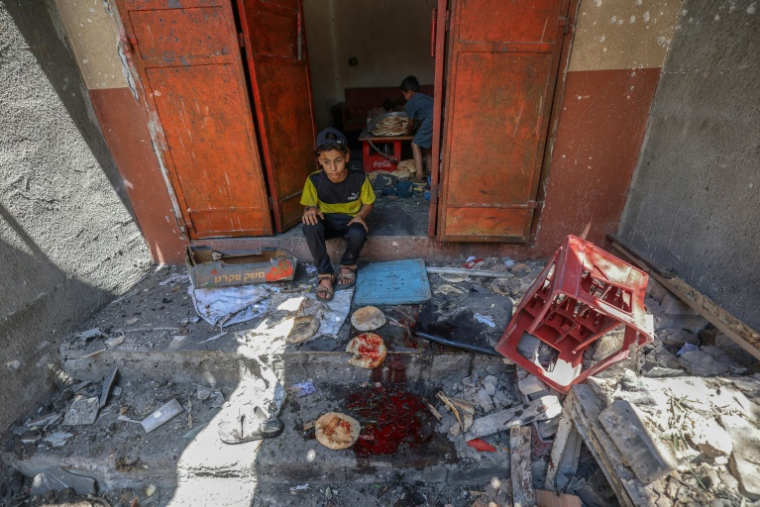 Des enfants palestiniens récupèrent du pain dans une boulangerie détruite par des frappes israéliennes dans le camp de réfugiés de Nousseirat, dans le centre de la bande de Gaza, le 8 mai 2025 ( AFP / Eyad BABA )