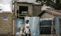 Un jeune homme marche dans un quartier de Cotonou le 9 avril 2026, près d'une affiche électorale placardée au mur  ( AFP / OLYMPIA DE MAISMONT )