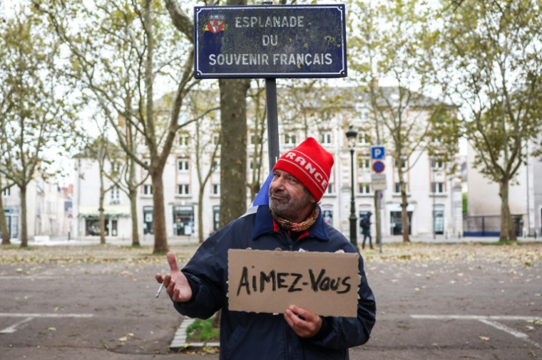 Un manifestant devant le panneau de l'esplanade du Souvenir français à Orléans, tient une pancarte sur laquelle est inscrit "Aimez-vous", le 24 octobre 2026  ( AFP / ROMAIN PERROCHEAU )