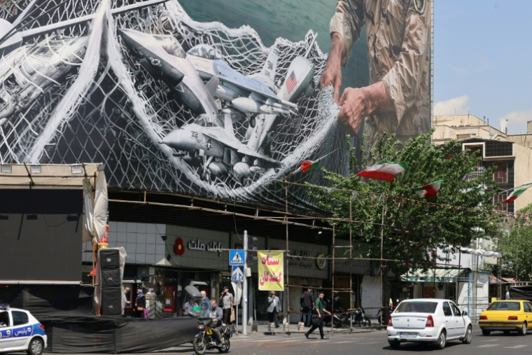 Des véhicules passent devant un immense panneau d'affichage sur lequel est écrit "Le détroit d'Ormuz reste fermé", sur la place de la Révolution à Téhéran, le 28 avril 2026, en Iran ( AFP / ATTA KENARE )