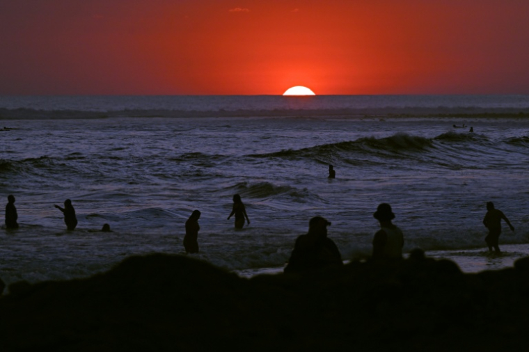 Des touristes se baignent au soleil couchant sur la plage d'El Tunco, à La Libertad, au Salvador, le 13 février 2026 ( AFP / Marvin RECINOS )
