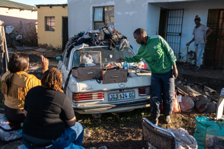 Des habitants rassemblent leurs affaires dans une cour après des inondations hivernales, le 12 juin 2025 près de Mthatha, en Afrique du Sud ( AFP / EMMANUEL CROSET )